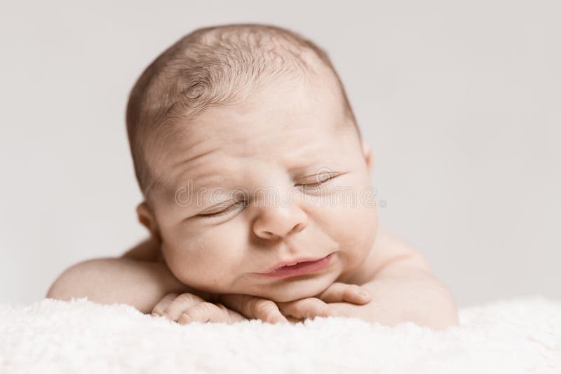 Homem recém-nascido do bebê que dorme com cara enrugada imagem de stock Homem recém-nascido do bebê que dorme com cara enrugada imagem de stock