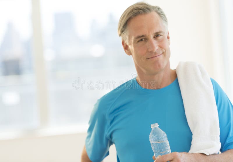 Homem seguro com toalha e garrafa de água no clube imagem de stock royalty free Homem seguro com toalha e garrafa de água no clube imagem de stock royalty free