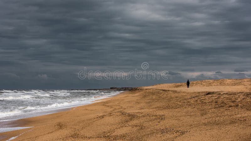 Homem solitário caminha pela costa marítima imagens de stock royalty free Homem solitário caminha pela costa marítima imagens de stock royalty free