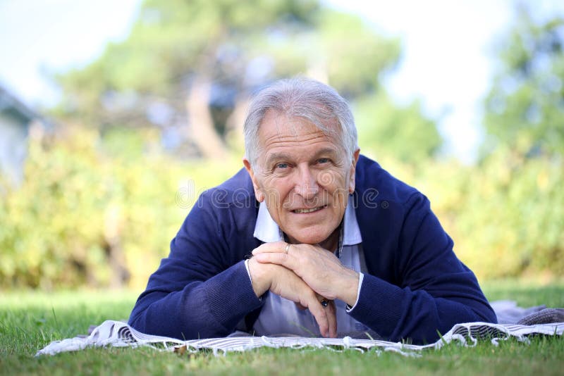 Homem superior que relaxa na grama fotografia de stock Homem superior que relaxa na grama fotografia de stock