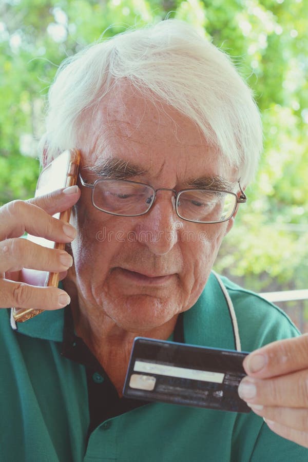 Homem superior que usa um cartão de crédito sobre o telefone imagens de stock royalty free Homem superior que usa um cartão de crédito sobre o telefone imagens de stock royalty free