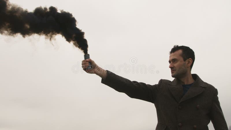 Homem sério que guarda a bomba de fumo com emanações pretas