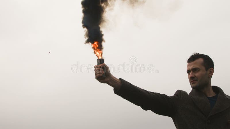 Homem sério que guarda a bomba de fumo com emanações pretas