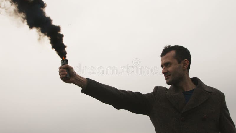 Homem sério que guarda a bomba de fumo com emanações pretas