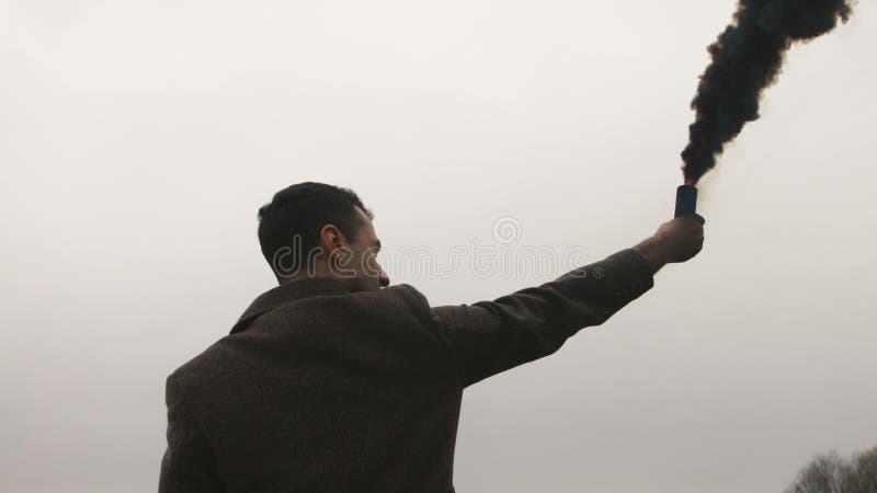 Homem sério que guarda a bomba de fumo com emanações pretas