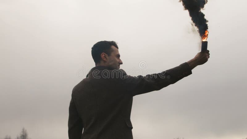 Homem sério que guarda a bomba de fumo com emanações pretas