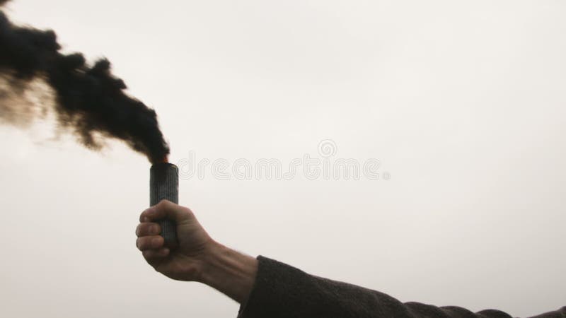 Homem sério que guarda a bomba de fumo com emanações pretas