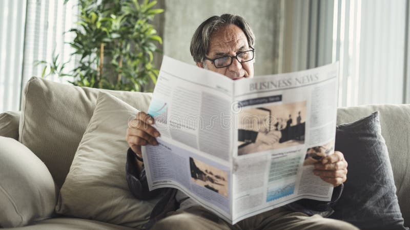 Homem sênior lendo jornal em casa fotos de stock Homem sênior lendo jornal em casa fotos de stock