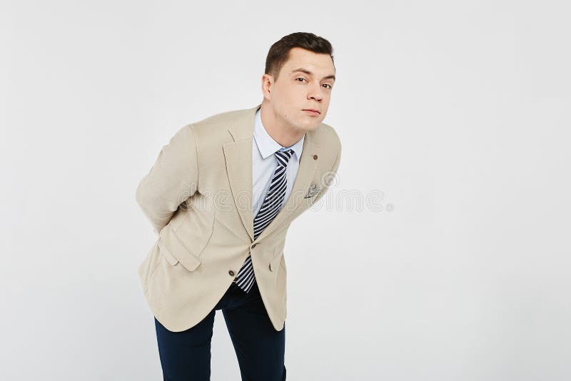Homem triguenho novo à moda e considerável na camisa branca com laço listrado, em um revestimento desportivo bege e em calças de imagens de stock Homem triguenho novo à moda e considerável na camisa branca com laço listrado, em um revestimento desportivo bege e em calças de imagens de stock