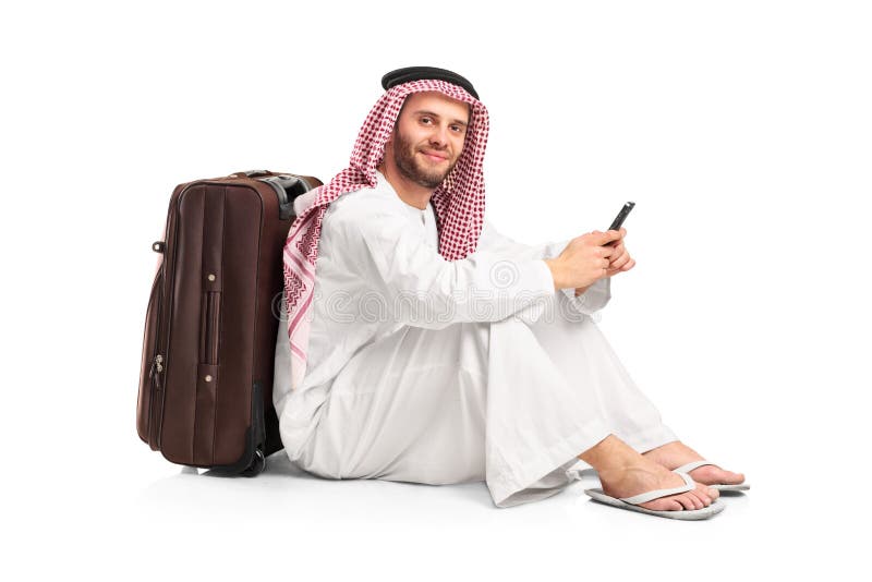 Homem árabe que senta-se perto de uma mala de viagem imagens de stock Homem árabe que senta-se perto de uma mala de viagem imagens de stock
