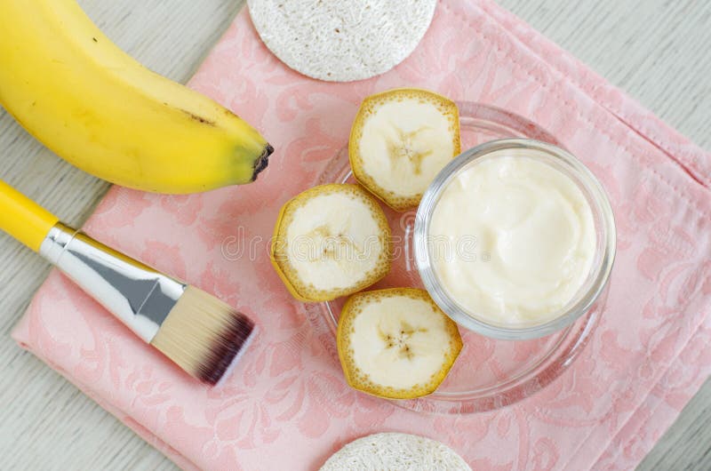 Homemade banana face mask cream in the small glass jar and cosmetic brush. DIY beauty treatments and spa. Top view, copy space