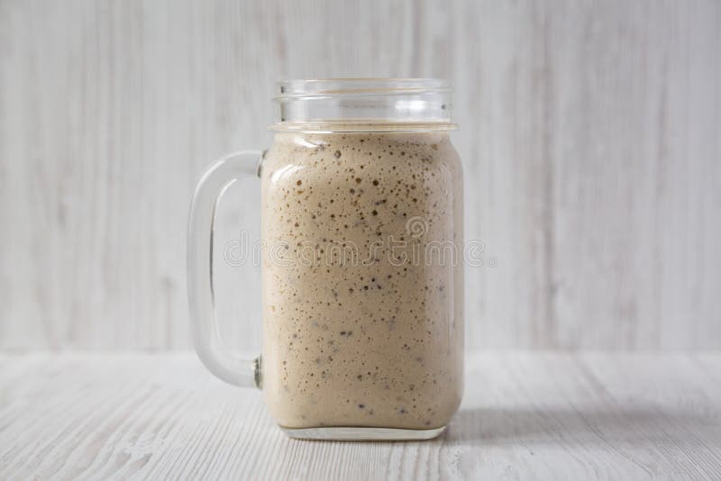 Homemade banana, kiwi, apple smoothie in a glass jar mug over white wooden background, side view. Close-up stock photo Homemade banana, kiwi, apple smoothie in a glass jar mug over white wooden background, side view. Close-up stock photo