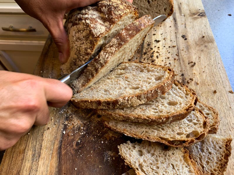 Homemade Bread Being Sliced On A Wooden Cutting Board During Covid19 Homemade Bread Being Sliced On A Wooden Cutting Board During Covid19