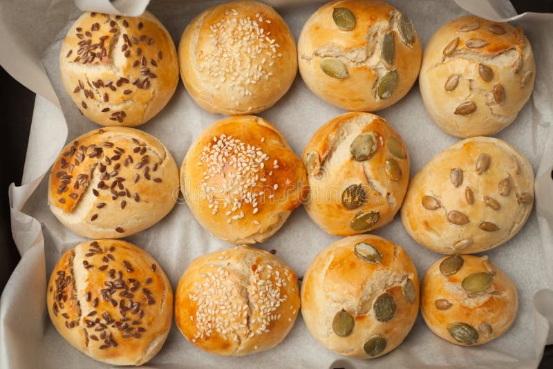 The homemade bread rolls with sesame seeds hamburger with sesame, pumpkin, flax, sunflower seeds on the tray, concept of burger