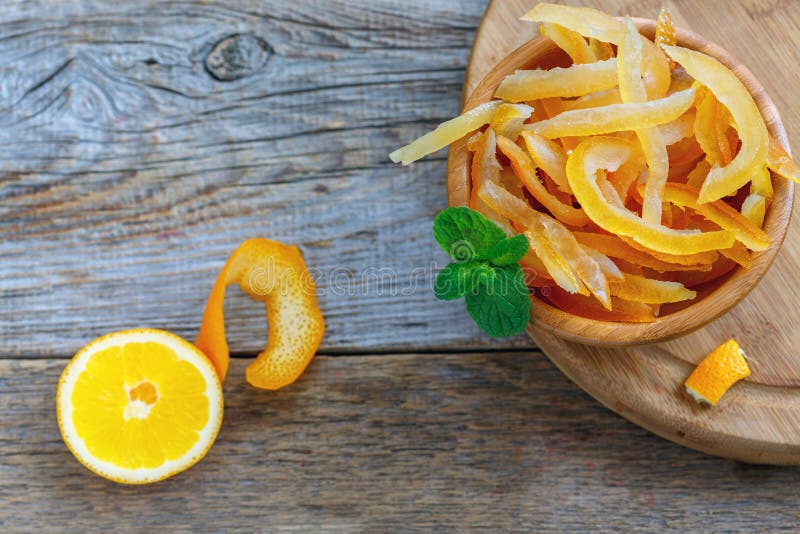 Candied orange and lemon peels in a wooden bowl on old table. Candied orange and lemon peels in a wooden bowl on old table.