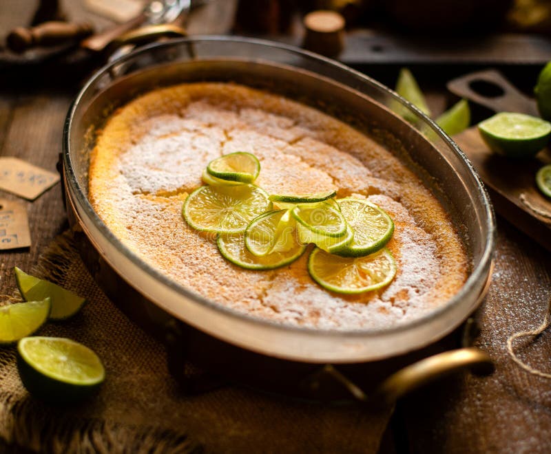 Homemade casserole, pudding, cheesecake, mousse with lime in glass baking dish stands on rustic wooden brown table