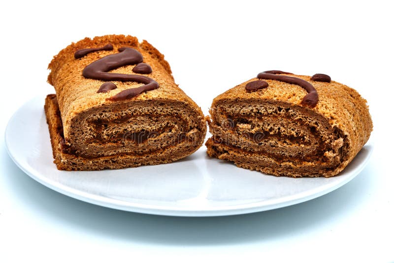 Homemade chocolate roll on plate, isolate on white background. Handmade pastries sprinkled with cocoa. Delicious chocolate-covered