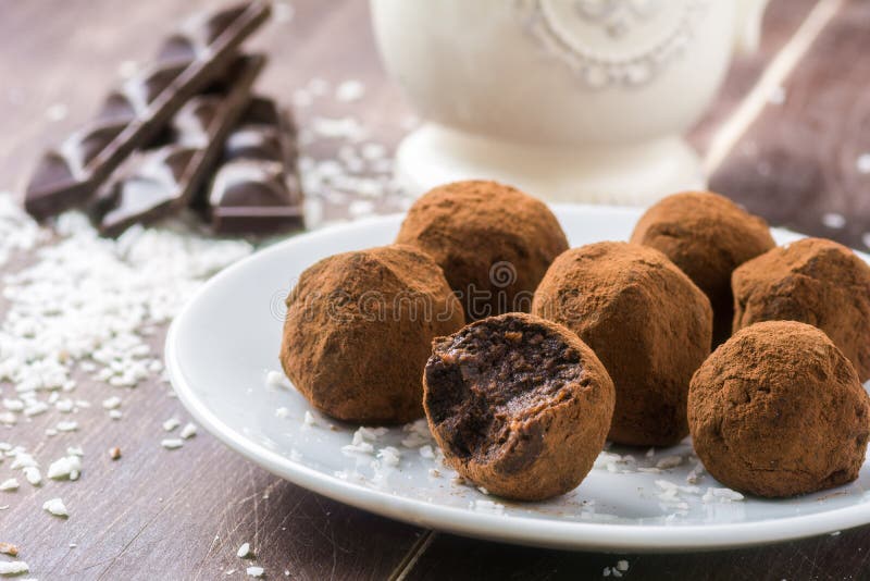 Setoso cancellare domestico cioccolato tartufi noce di cocco fiocchi sul bianco in giro piatto.