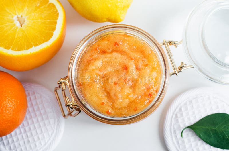 Homemade citrus fruit facial mask exfoliating sugar scrub in the glass jar. Mandarin, orange, lemon DIY cosmetics and spa recipe. Top view, Copy space.