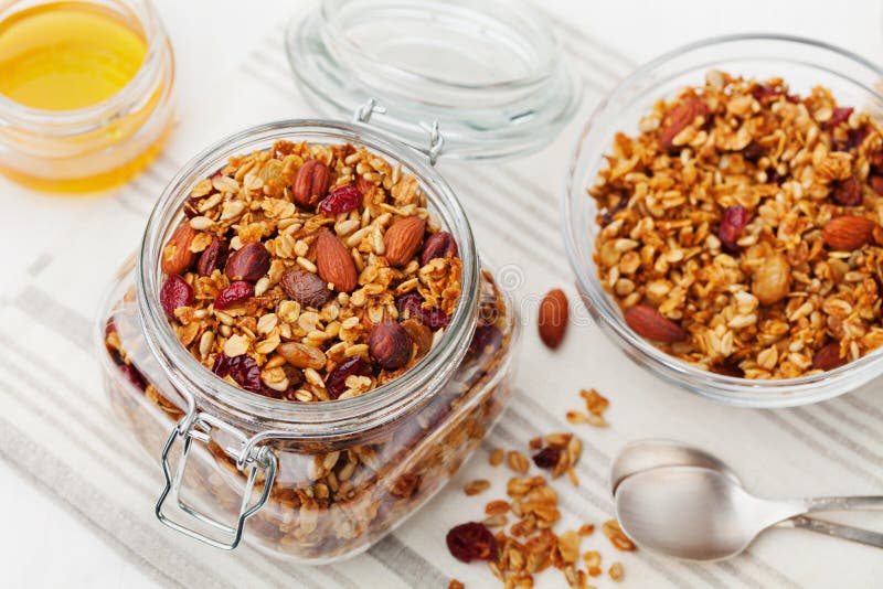 Homemade granola in jar on white table, healthy breakfast of oatmeal muesli, nuts, seeds and dried fruit royalty free stock photo Homemade granola in jar on white table, healthy breakfast of oatmeal muesli, nuts, seeds and dried fruit royalty free stock photo