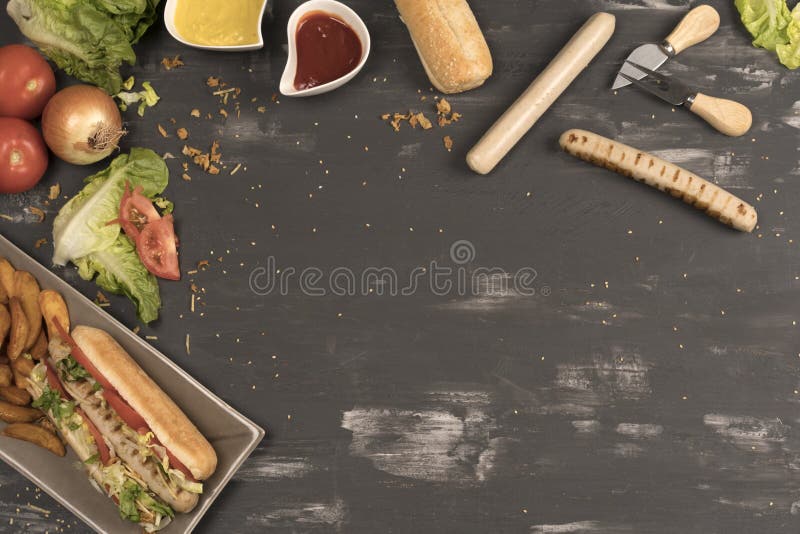 Homemade hot dog with white sausages with various condiments on gray table seen from above