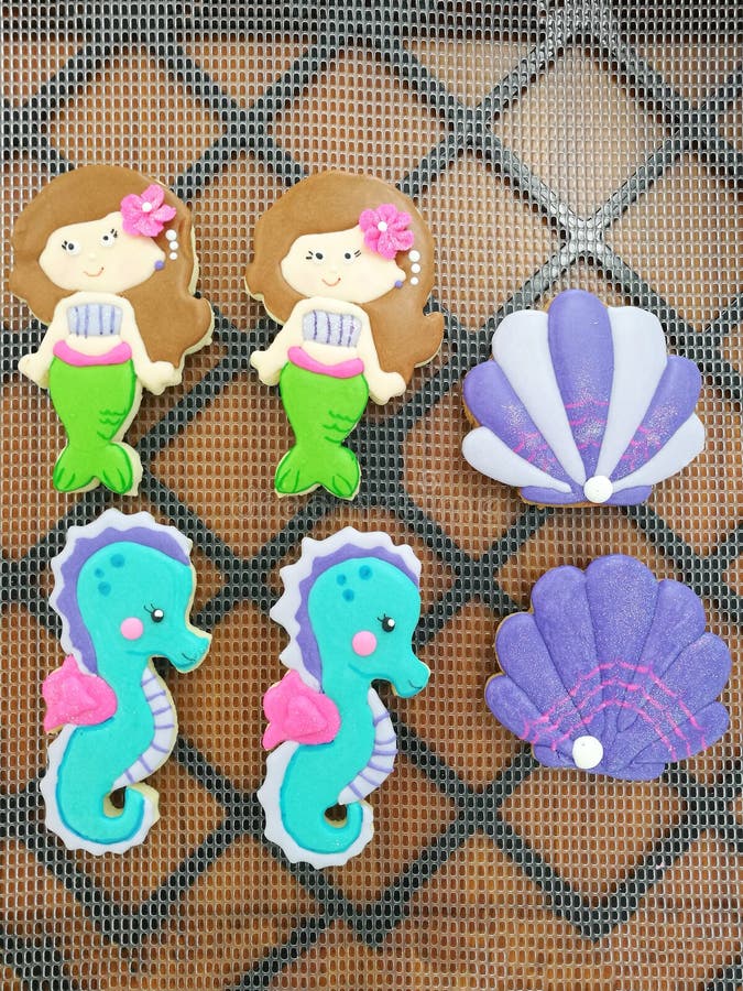 Homemade icing sugar cookies in the shape of a mermaid, oyster and seahorse. Top view. Vertical shot.