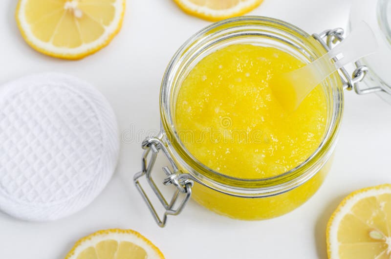 Homemade lemon facial mask exfoliating sugar scrub in the glass jar. DIY citrus beauty treatment and spa recipe. Top view, copy space.