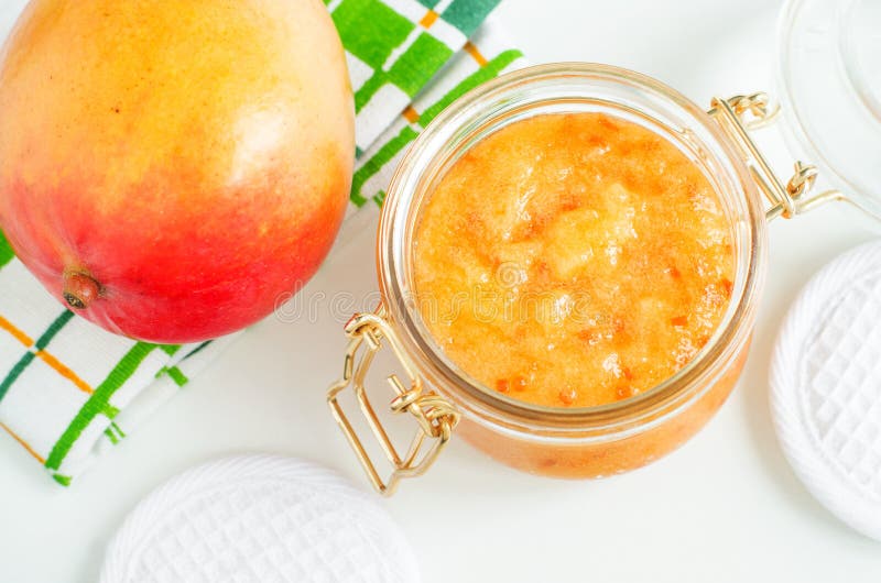 Homemade mango facial mask exfoliating face and body sugar scrub in the glass jar. Fruit DIY beauty treatment and spa recipe. Top view, copy space. Homemade mango facial mask exfoliating face and body sugar scrub in the glass jar. Fruit DIY beauty treatment and spa recipe. Top view, copy space
