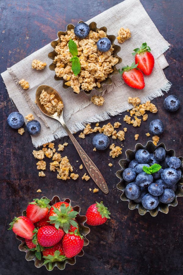 Homemade muesli granola in bowl with berries on rusty table