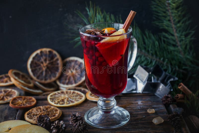 Homemade mulled wine with oranges, apples, cinnamon, cranberries and fir tree on rustic wooden background. Hot Christmas or New Year drink, holiday food concept, selective focus