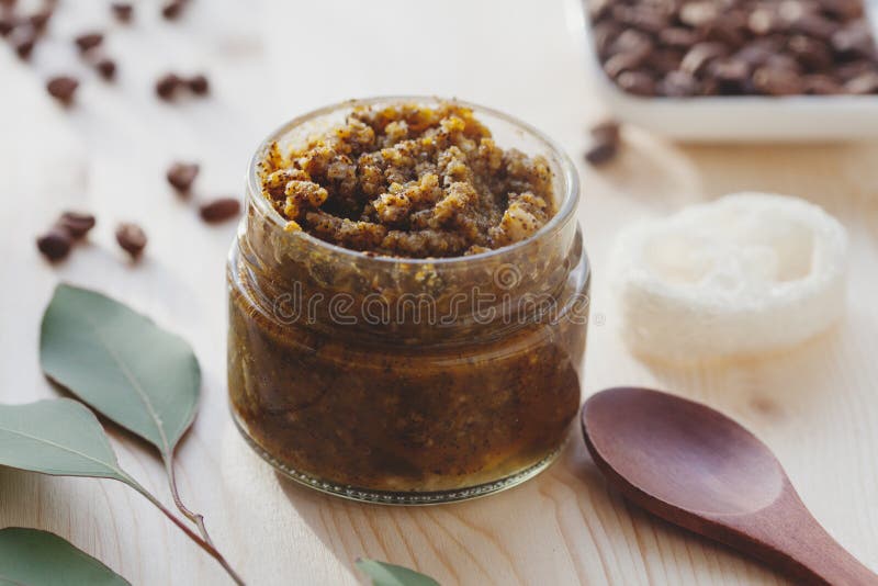 Homemade natural scrub made of salt or sugar, coffee and coconut oil, bath towel, eucalyptus branch and sea sponge on wooden table