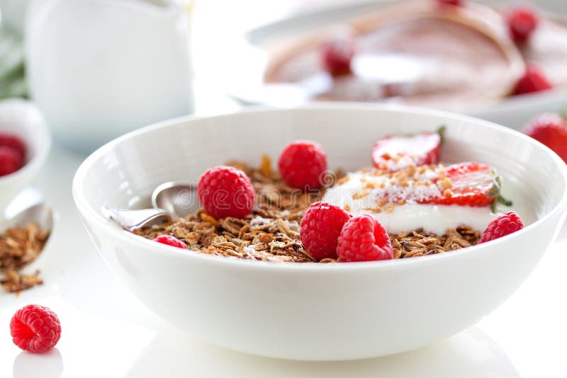 Homemade oat meal granola or muesli with fresh summer fruits â€“ raspberry and strawberry with yogurt