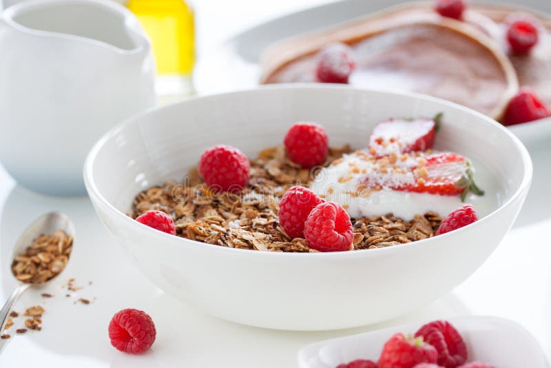 Homemade oat meal granola or muesli with fresh summer fruits â€“ raspberry and strawberry with yogurt