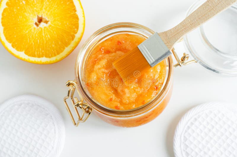 Homemade orange fruit facial mask exfoliating sugar scrub in the glass jar. Citrus DIY beauty treatment and spa recipe. Top view, copy space