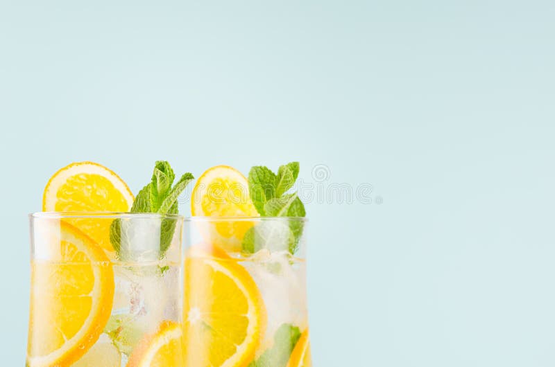 Homemade oranges lemonades with slices, ice cubes, mint in wet wineglasses on blue background, closeup, top section, edge. Homemade oranges lemonades with stock photos Homemade oranges lemonades with slices, ice cubes, mint in wet wineglasses on blue background, closeup, top section, edge. Homemade oranges lemonades with stock photos