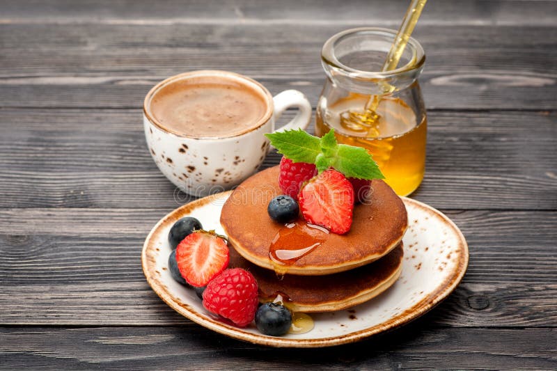 Homemade pancakes with honey, espresso and berries