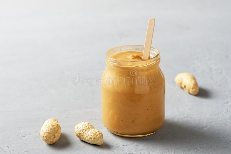 Homemade Peanut Butter in a Glass Jar on a Concrete Surface Stock Photo