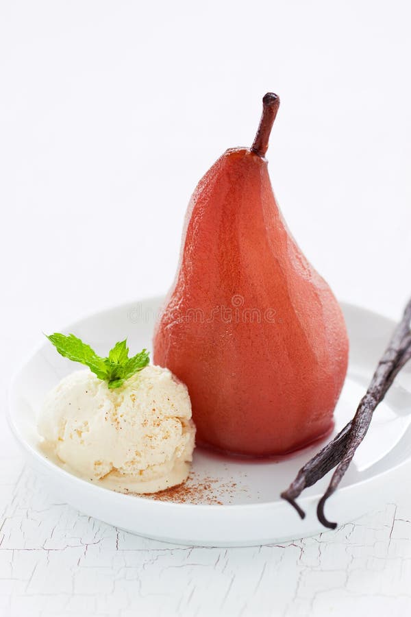 Homemade poached pear with vanilla ice cream, mint and vanilla sticks