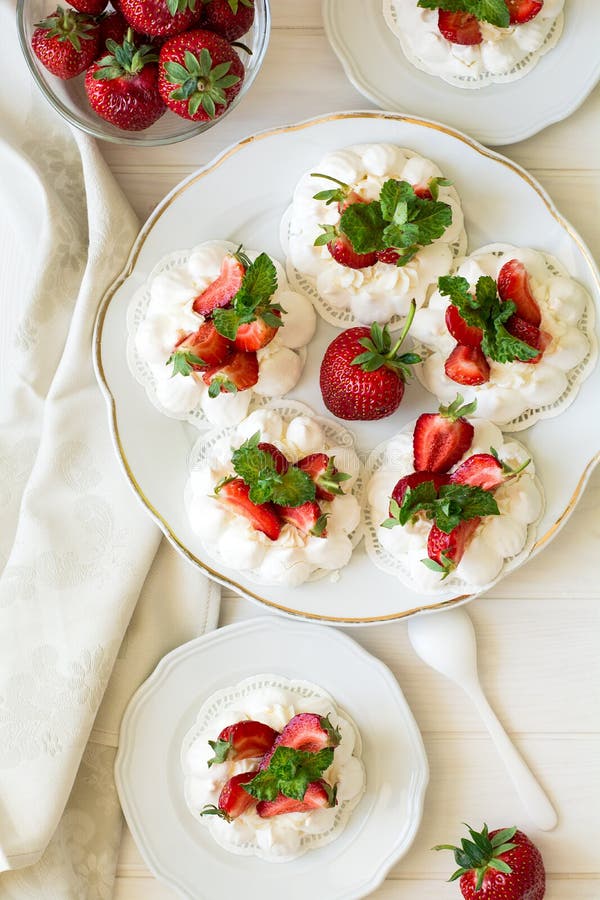 Homemade small strawberry pavlova meringue cakes with mascarpone cream and fresh mint leaves