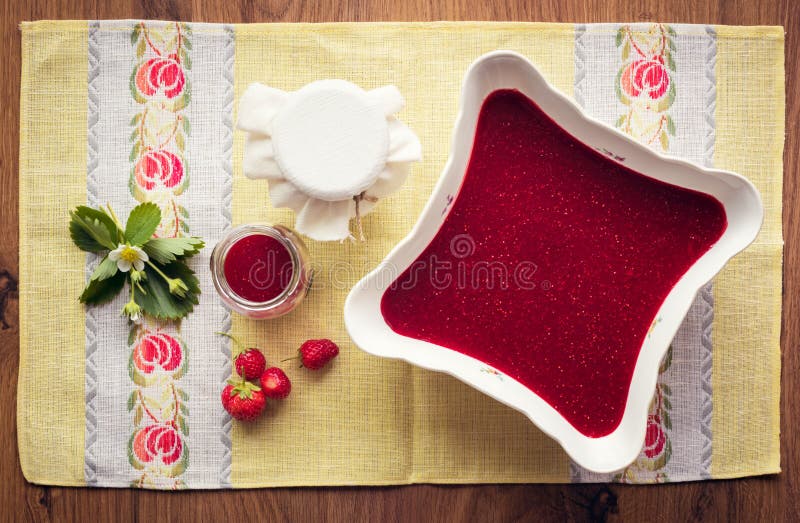 Homemade strawberry jam (marmelade) in jars on wooden background.