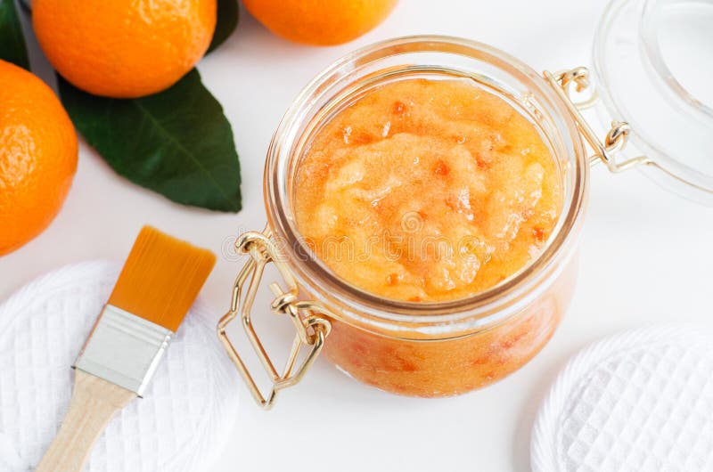 Homemade tangerine facial mask exfoliating sugar scrub in the glass jar. Mandarin orange DIY cosmetics and spa recipe. Top view, Copy space.