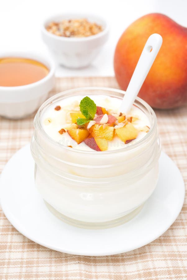 Homemade yogurt with honey, peaches and nuts in a glass jar