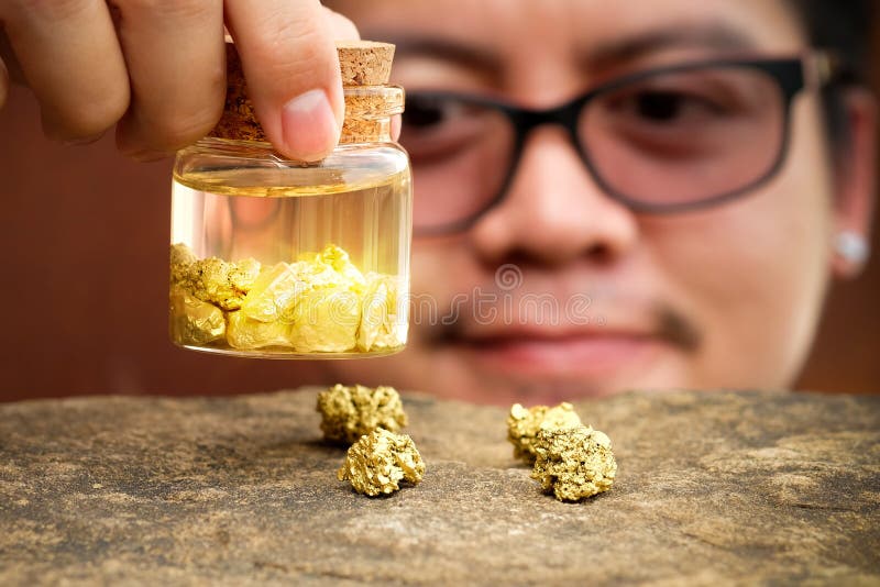 Homens asiáticos que sorriem e que olham o ouro na garrafa imagens de stock royalty free Homens asiáticos que sorriem e que olham o ouro na garrafa imagens de stock royalty free
