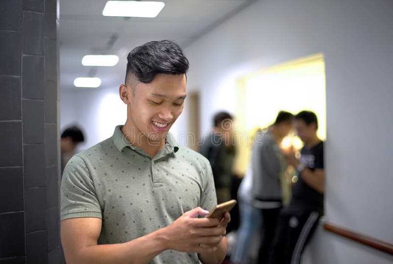 Homens consideráveis asiáticos que falam felizmente no telefone | Sorriso do indivíduo ao datilografar o smartphone da mensage foto de stock royalty free Homens consideráveis asiáticos que falam felizmente no telefone | Sorriso do indivíduo ao datilografar o smartphone da mensage foto de stock royalty free