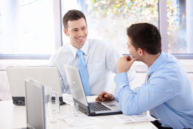 Homens de negócios consideráveis que conversam na sala de reunião foto de stock Homens de negócios consideráveis que conversam na sala de reunião foto de stock