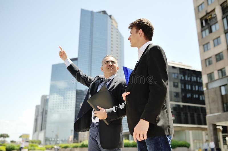 Homens de negócios que falam sobre o projeto de trabalho em construções incorporadas do escritório moderno do fundo foto de stock Homens de negócios que falam sobre o projeto de trabalho em construções incorporadas do escritório moderno do fundo foto de stock