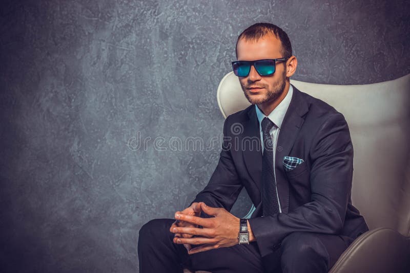 Homens de negócios 'sexy' brutais no terno com laço e óculos de sol que sentam-se na cadeira fotos de stock royalty free Homens de negócios 'sexy' brutais no terno com laço e óculos de sol que sentam-se na cadeira fotos de stock royalty free