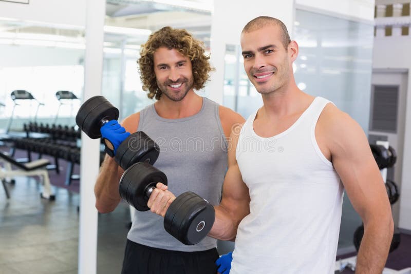 Homens desportivos que exercitam com pesos no gym fotografia de stock Homens desportivos que exercitam com pesos no gym fotografia de stock