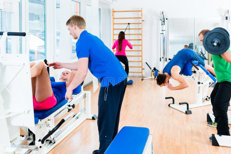 Homens e mulheres que fazem o exercício no equipamento diverso no gym foto de stock royalty free Homens e mulheres que fazem o exercício no equipamento diverso no gym foto de stock royalty free