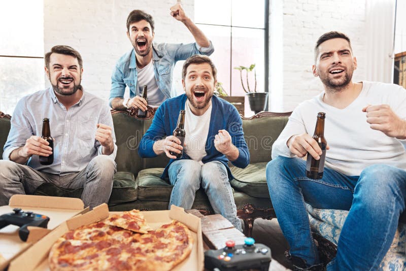 Homens felizes agradáveis que apoiam sua equipa de futebol imagens de stock Homens felizes agradáveis que apoiam sua equipa de futebol imagens de stock